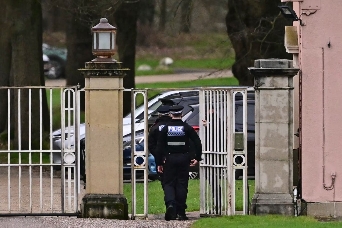 Police officers walk through the gated entrance to Royal Lodge, a 30-room property and former residence to Britain's former prince Andrew where police said they are still conducting a search, in Windsor, west of London on February 20, 2026, a day after Andrew Mountbatten-Windsor was arrested on the royal family's remote Sandringham estate in eastern England.