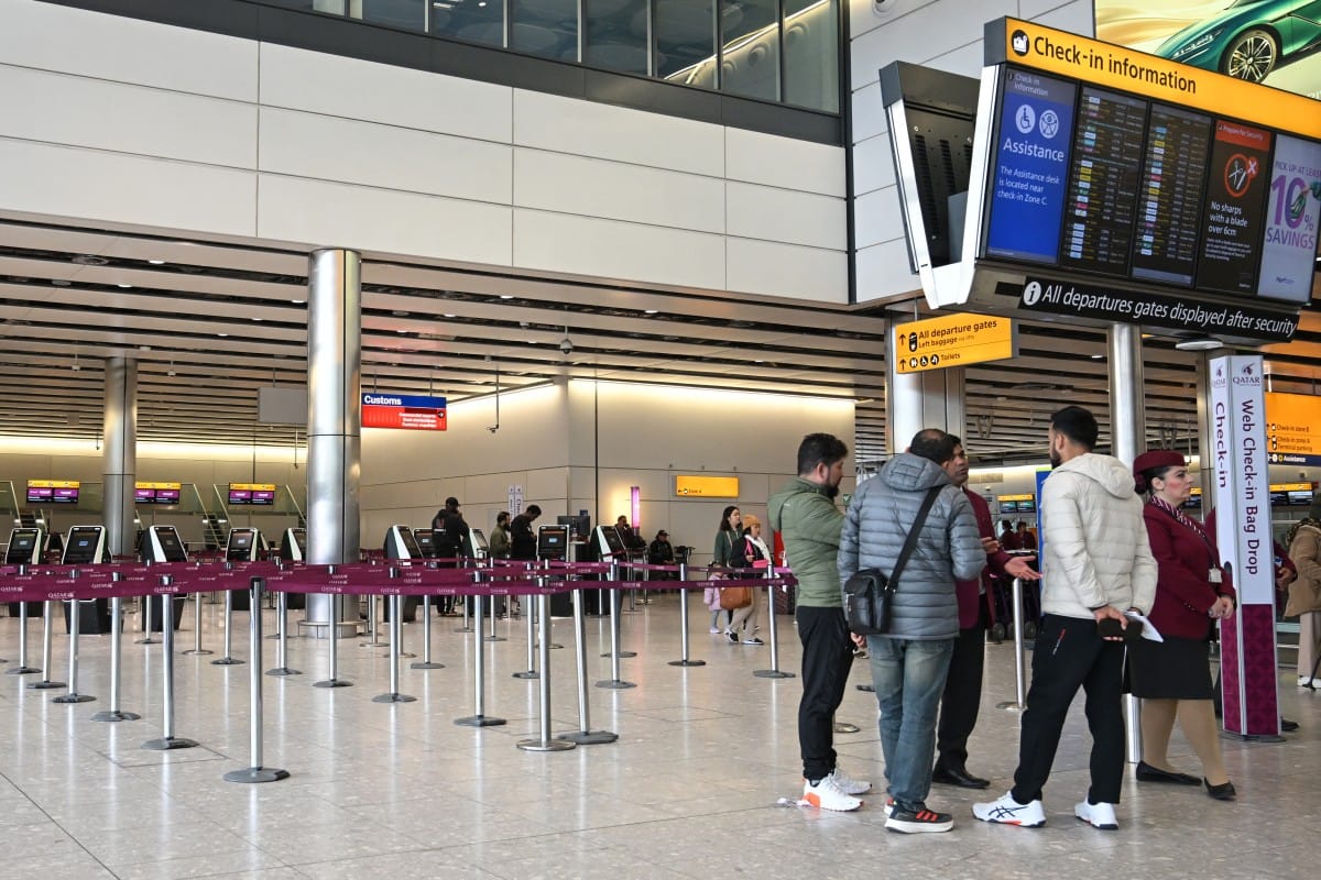 Staff (R-in uniform) from Qatar Airways help assist people with questions at their check-in area at London Heathrow Airport in west London on March 1, 2026, as flights are severely disrupted following the US and Israel's strikes on Iran. Photo used for illustrative purposes. 