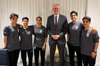 Australia's Minister for Home Affairs Tony Burke (C) poses in an undisclosed location with five Iranian women soccer players who have been granted asylum in Australia, on March 10, 2026.
