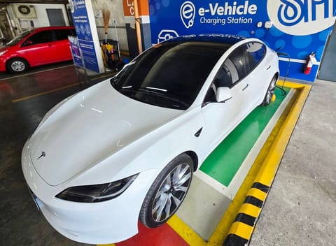 Filipino businessman Glenn Cuarto, a former OFW from the UAE, charges his Tesla Model 3 at a local mall (SM City Iligan, in Mindanao). Plug-in car sales have jumped 600% in February alone, before the Middle East war erupted.