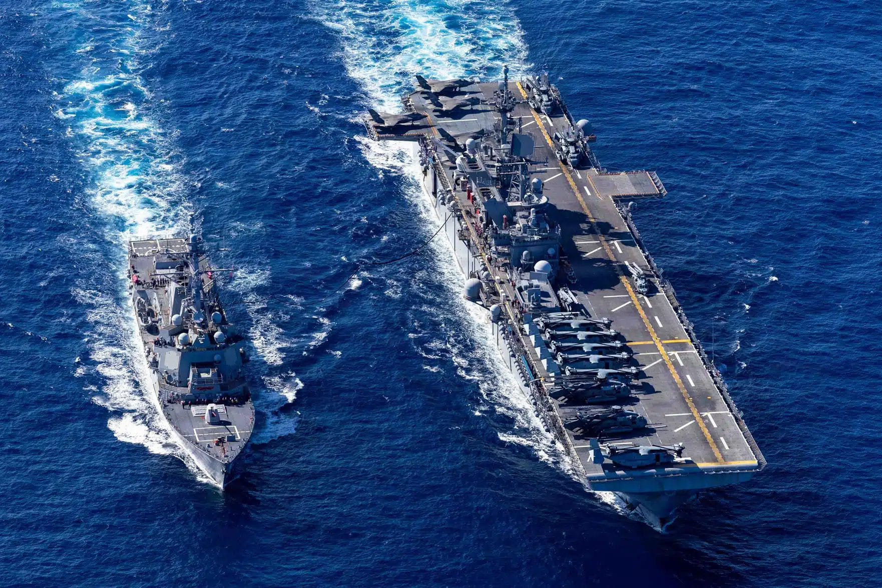 The US Navy destroyer USS Rafael Peralta refuels from the amphibious assault ship USS Tripoli during operations at sea. Amphibious ships like the Tripoli can deploy Marine Expeditionary Units during crises such as the current Iran war.