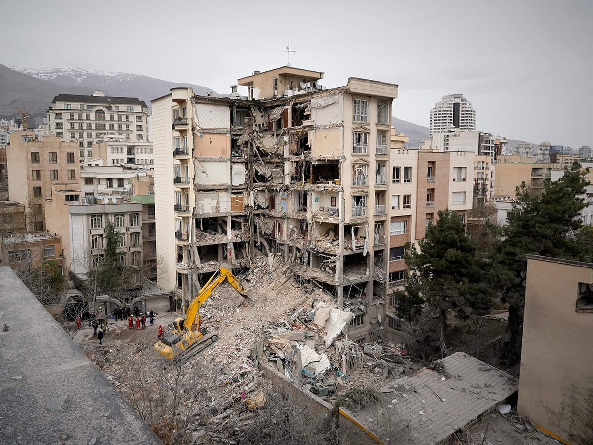 Iranian Red Crescent emergency workers use a bulldozer to clear rubble from a residential building that was hit in an earlier US-Israeli strike in Tehran, Iran, Monday, March 23, 2026. 