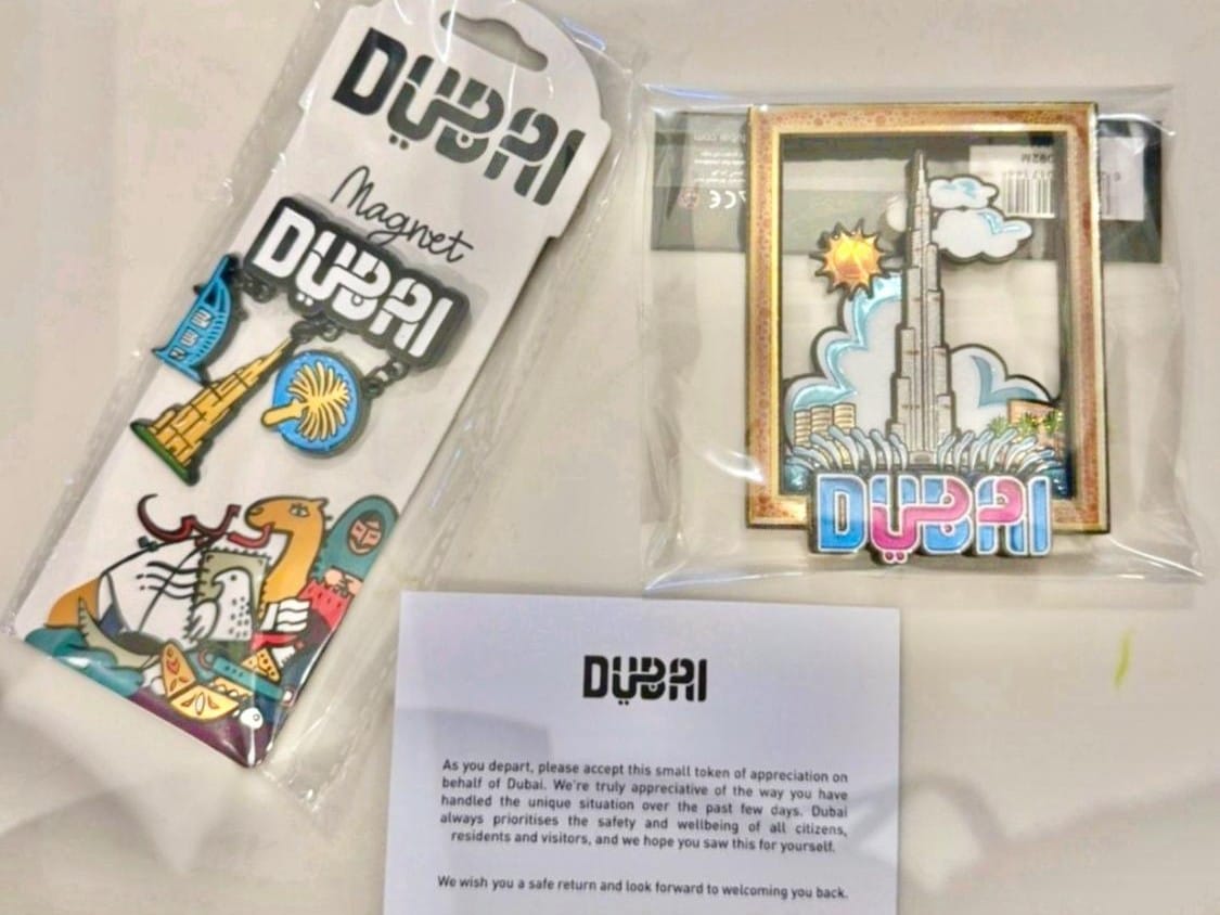The thank-you note accompanies souvenirs that include Dubai-themed fridge magnets featuring the Burj Khalifa and a license plate magnet featuring Dubai skyline, among others.