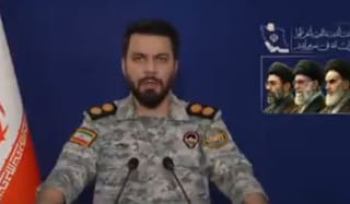 An Iranian military spokesperson with portraits of the late Khamenei and present supreme leader and his son Mojtaba Khamenei in the background — as hardline forces shape Tehran’s stance on US peace efforts.