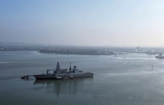 An aerial view shows HMS Dragon, a Royal Navy Type 45 Daring-class air-defence destroyer warship, moored at the HMNB Portsmouth Upper Harbour Ammunition Facility (UHFC), outside HM Naval Base Portsmouth, pictured from Gosport, on the south coast of England, on March 4, 2026.