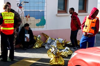 A man sits next to rescue units after an attempt to cross the English Channel illegally turned tragic with several migrants found in cardiac arrest, in France's Pas-de-Calais northern coastal city of Equihen-Plage on April 9, 2026.