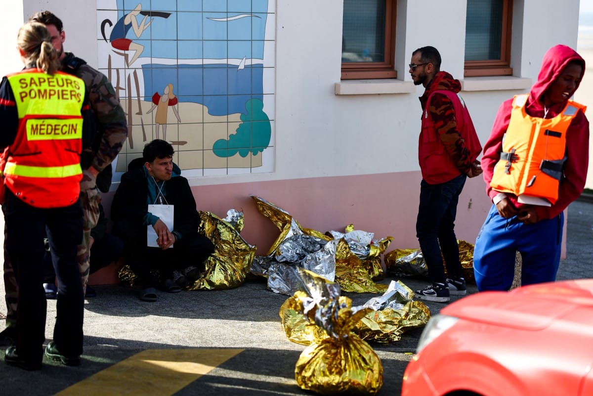 A man sits next to rescue units after an attempt to cross the English Channel illegally turned tragic with several migrants found in cardiac arrest, in France's Pas-de-Calais northern coastal city of Equihen-Plage on April 9, 2026.