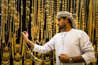 A gold dealer arranges a necklace in a jewellery shop at the Dubai Gold Souk earlier this week.