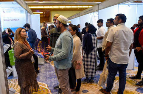 Parents interacting with exhibitors to gather information on courses and universities 