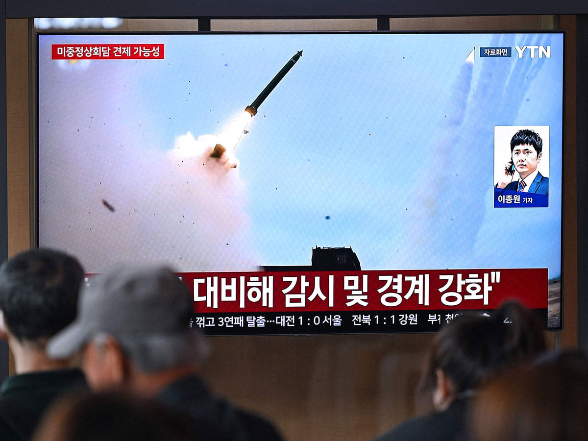 People watch a television screen showing a news broadcast with file footage of a North Korean missile test, at a train station in Seoul on April 19, 2026.