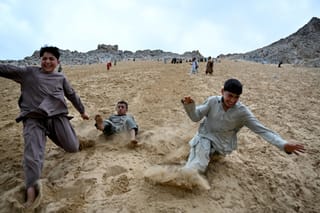 Afghan visitors enjoy rolling down a steep and sandy mountainside on a weekend at the Sayad area of Reg-e-Rawan in Kapisa province.