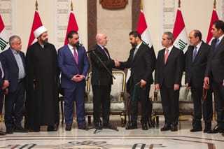 This handout photograph taken and released by the Iraqi Presidency Press Office on April 27, 2026 shows Iraq's President Nizar Amede (4th L) shaking hands with newly Iraq's Prime Minister designated Ali al-Zaidi (4th R), surrounded by Iraqi political leaders, at the Presidential Palace in Bagdad.