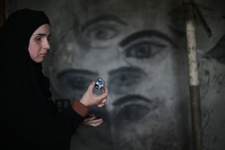 Areej al-Saafin, who lost her eye as a result of an Israeli military strike, holds a piece of wood charcoal as she prepares to draw on the wall of her home in the Bureij Palestinian refugee camp in the central Gaza Strip.