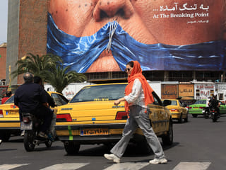 Commuters walk past an anti-US billboard referring to President Donald Trump and the Strait of Hormuz, installed on a building at the Valiasr Square in Tehran on May 2, 2026. 