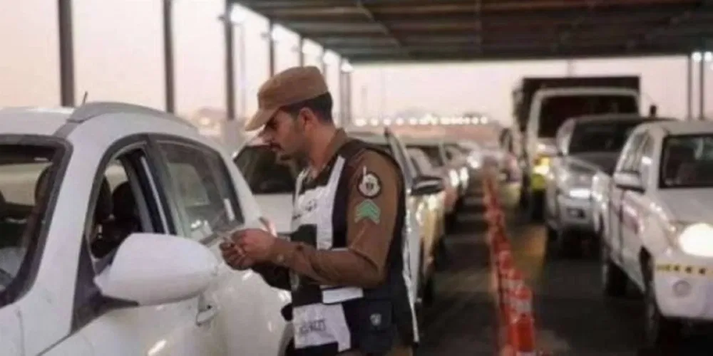 Saudi police man verifies ID documents and Hajj permits at a checkpoint.  