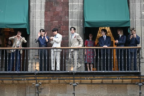 Mexico's President Claudia Sheinbaum looks at South Korean K-pop band BTS as they acknowledge fans from the balcony of the National Palace, at Zocalo square in Mexico City on May 6, 2026.