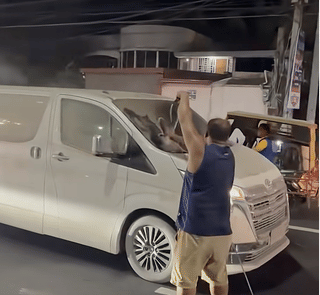 A man is shown clearing the windscreen of a passing vehicles affected by the volcanic ash fall in Albay. Millions of tonnes of volcanic ash blanketed a huge swath of Albay province, affecting nearby towns, burying roads, rooftops and fields under a blanket of volcanic debris.