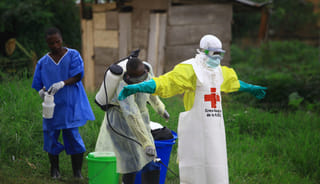 A health worker sprays disinfectant on his colleague after working at an Ebola treatment center in Beni