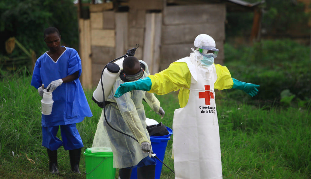 A health worker sprays disinfectant on his colleague after working at an Ebola treatment center in Beni