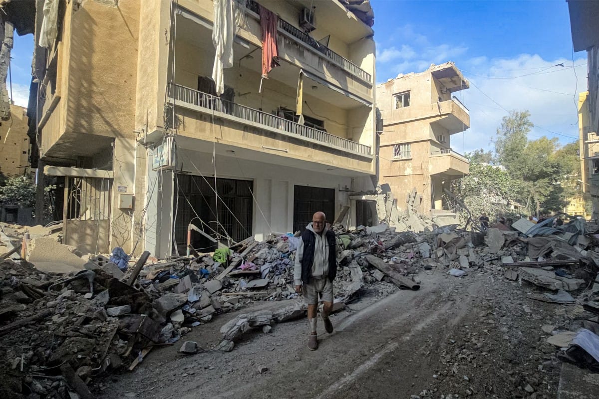 People stand by rubble and debris near damaged and collapsed buildings following overnight Israeli bombardment on Lebanon's southern city of Tyre on May 16, 2026.