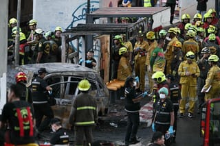 Forensic police officers, rescue workers and firefighters stand at the site of a train collision with a bus underneath Makkasan Airport Rail station in Bangkok on May 16, 2026.