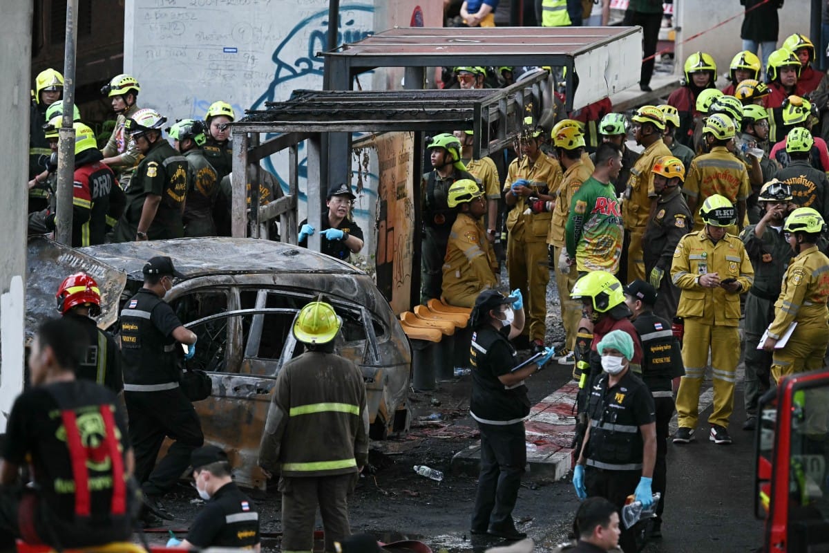 Forensic police officers, rescue workers and firefighters stand at the site of a train collision with a bus underneath Makkasan Airport Rail station in Bangkok on May 16, 2026.