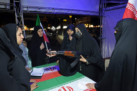 An Iranian military personnel educates women about how to use a gun at a booth in Hafte Tir Square, in Tehran on May 17, 2026. 