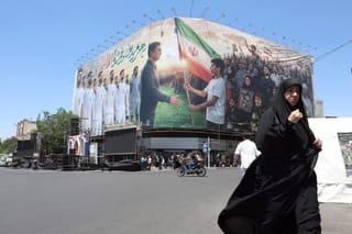 An Iranian woman walks past a huge billboard supporting Iran’s national football team in the upcoming 2026 World Cup, installed on a building at Enghelab Square in Tehran on May 18, 2026.