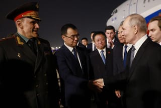 In this pool photograph distributed by the Russian state agency Sputnik, Russia's President Vladimir Putin is welcomed by Chinese Foreign Minister Wang Yi and other officials upon his arrival at Beijing Capital Airport in Beijing late on May 19, 2026.