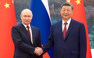In this pool photograph distributed by the Russian state agency Sputnik, Russia's President Vladimir Putin (L) shakes hands with China's President Xi Jinping during a meeting in Beijing on May 20, 2026.