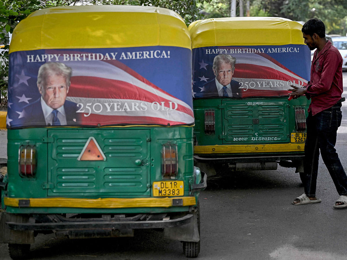 A worker fixes a poster featuring US President Donald Trump on an autorickshaw in New Delhi on May 21, 2026 marking the 250th anniversary of American independence.