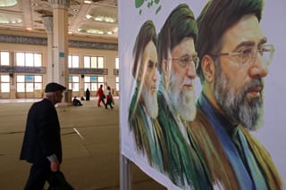 An Iranian man walks past an image of former and the current Iranian supreme leaders during a commemoration for those killed in former wars and also those killed during the latest US-Israel led war, in Tehran on May 24, 2026.