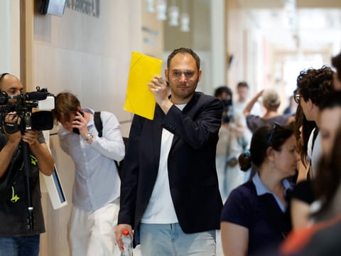 David G., an after-school staff member who is accused of sexually assaulting preschool pupils, hides his face from a TV camera as he arrives on the first day of his trial at The Paris Courthouse, in Paris on May 26, 2026.
