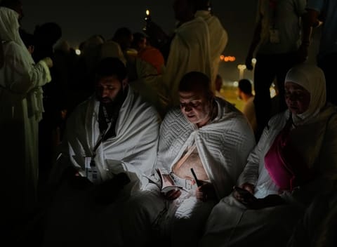 Muslim pilgrims read a copy of Islam's holy book Quran atop of the rocky hill known as the Mountain of Mercy, on the Plain of Arafat, during the annual Hajj pilgrimage near the holy city of Mecca, Saudi Arabia, Tuesday, May 26, 2026. (AP Photo/Altaf Qadri)