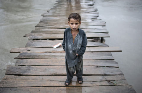 A child walks on a wooden bridge towards the village of Shah Alam on the outskirts of Peshawar in Pakistan (File) 