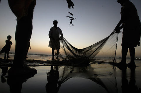 Pakistani fishermen pull their net out of the sea onto the beach in Karachi, Pakistan.
