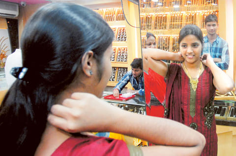 A woman tries a gold pendant at a jewellery shop in Mumbai,India. Picture for illustration purposes only. 