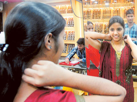 A woman tries a gold pendant at a jewellery shop in Mumbai,India. Picture for illustration purposes only. 