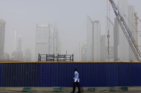 A man walks by a barrier during the hazy day in Dubai. 