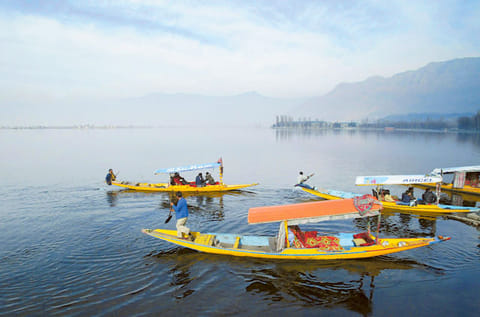 Kashmiri boatmen row their Shikara, a small boat, as tourists enjoy a ride in Dal Lake in  Srinagar. (File photo) 