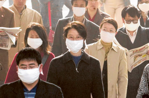 Chinese go to work at the height of the SARS scare. The WHO has warned against a new SARS-like virus.