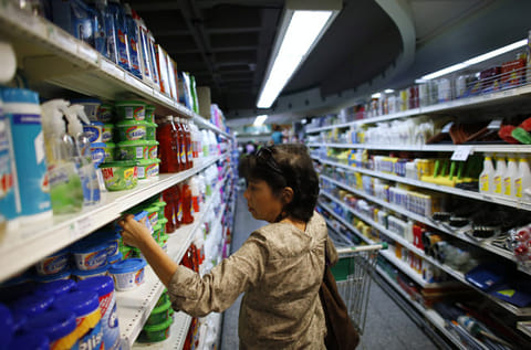 A woman looks at a product as she pushes a cart down an aisle in a supermarket in Caracas. Supplies of food and other basic products have been patchy in recent months, with long queues forming at supermarkets and rushes occurring when there is news of a new stock arrival. The situation has spawned jokes among Venezuelans, particularly over the lack of toilet paper. 