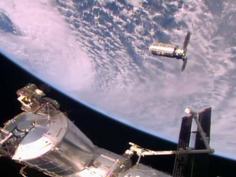 The Cygnus cargo ship slowly approaching the International Space Station (ISS) for docking.
