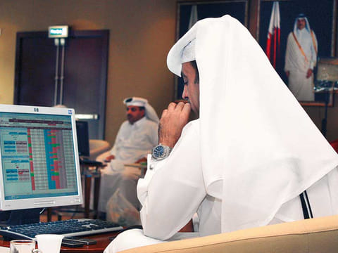 A trader tracks shares on a monitor at the Doha Stock Exchange. Qatar Exchange rose 0.8 per cent to 10,529 points returning to gains for the year.