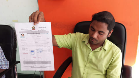 Abdul Rasheed, sales person at Abrar Al Madeena Studio in Abu Dhabi, holds an entry permit which he printed at his office. Photo for illustrative purposes.