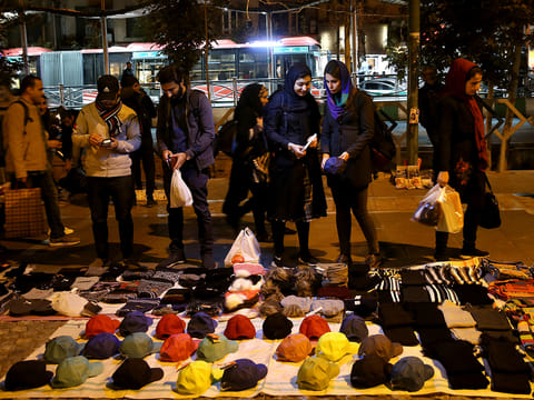 Pedestrians look at items of a vendor in downtown Tehran