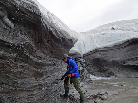 In a photo provided by Svend Funder, Kurt Kjær collecting sand samples at Hiawatha Glacier in Greenland. The sand was transported by the glacier from the bottom of the crater to the surface.