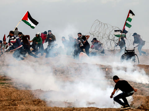 Palestinian demonstrators run for cover during a protest on November 16, 2018, on the eastern outskirts of Gaza City, near the border with Israel. 