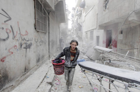 File photo: A boy carries his belongings at a site hit by a barrel bomb in Aleppo's Al Fardous district, Syria 