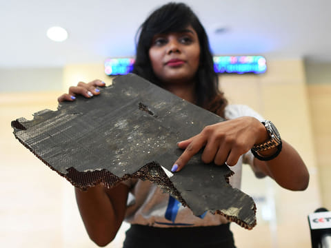 Grace Subathirai Nathan (R), daughter of Malaysian Airlines flight MH370 passenger Anne Daisy, shows a piece of debris believed to be from flight MH370 during a press conference in Putrajaya on November 30, 2018. 